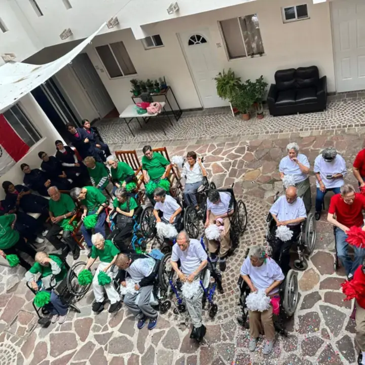 Residentes de Villas Legado Juan Pablo II celebrando las fiestas patrias con pompones verdes, blancos y rojos en el patio de la residencia